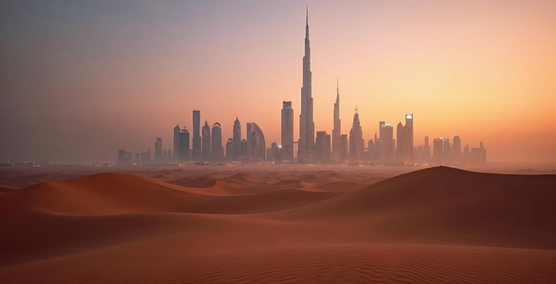 Dubai skyline with Burj Khalifa and desert dunes at dusk.